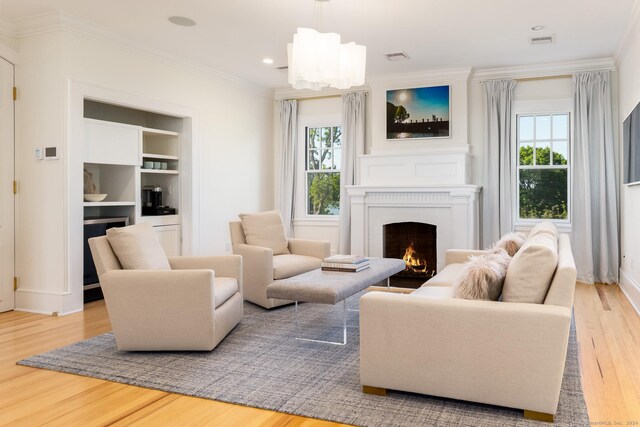 living room with a healthy amount of sunlight, crown molding, and light hardwood / wood-style flooring