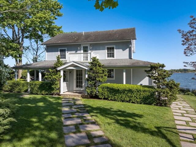 farmhouse inspired home with a front lawn and a balcony