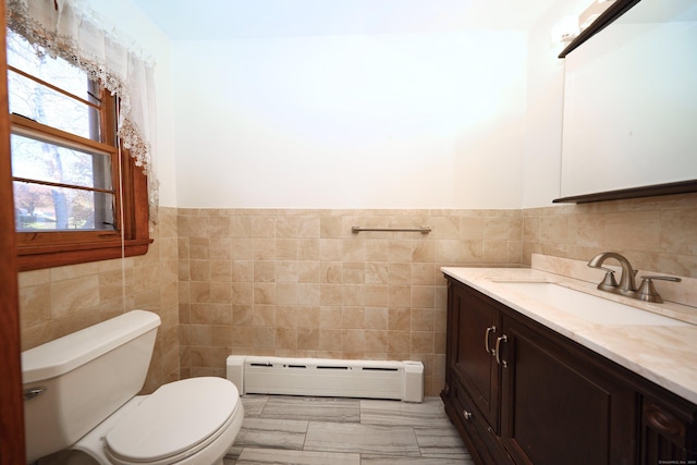 bathroom with vanity, toilet, tile walls, and a baseboard heating unit