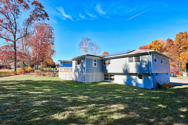 back of property featuring solar panels and a lawn