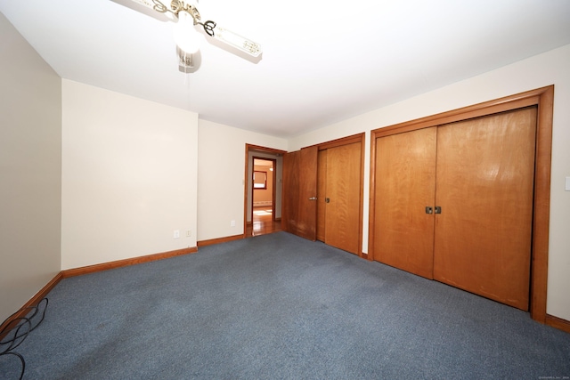 unfurnished bedroom featuring ceiling fan, carpet, and two closets