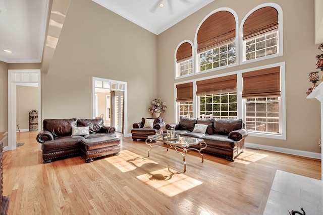 living room featuring light hardwood / wood-style flooring, a high ceiling, ceiling fan, and crown molding