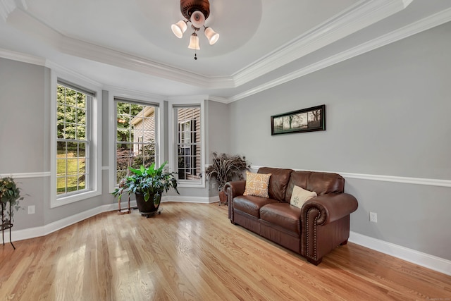 living area featuring ceiling fan, ornamental molding, a raised ceiling, and light hardwood / wood-style floors