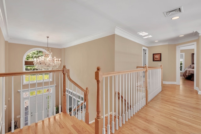 hallway with an inviting chandelier, light wood-type flooring, and crown molding