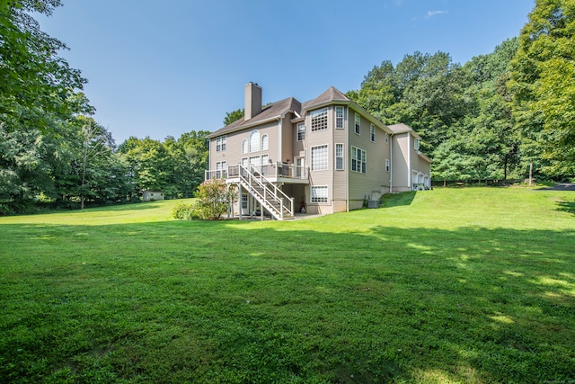 rear view of property featuring a deck and a lawn