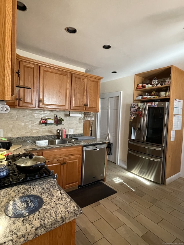 kitchen featuring appliances with stainless steel finishes, stone counters, sink, and tasteful backsplash