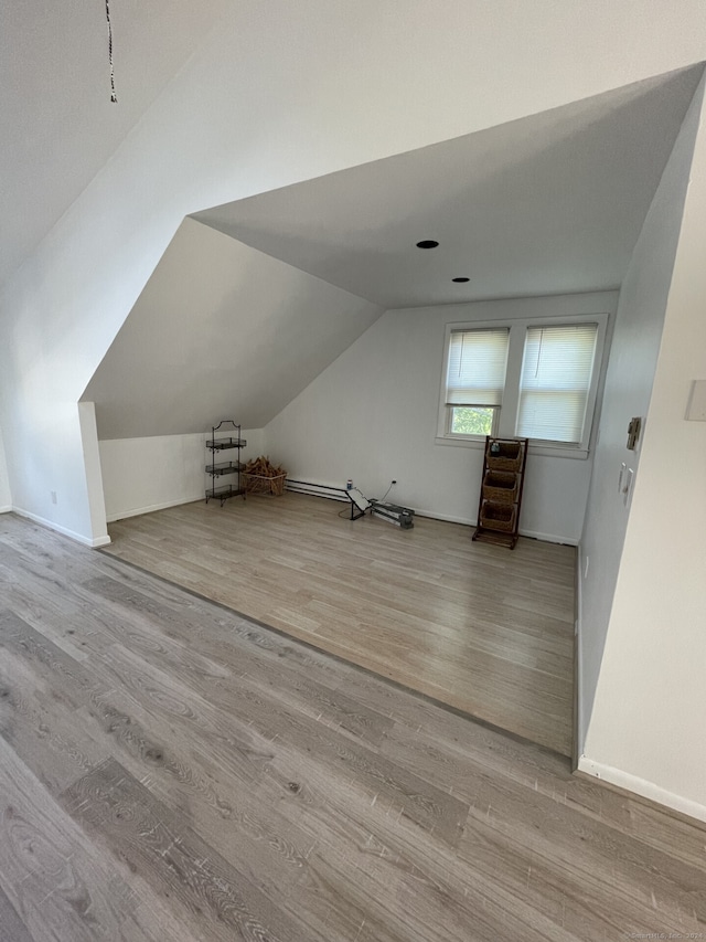 additional living space with vaulted ceiling and light hardwood / wood-style flooring