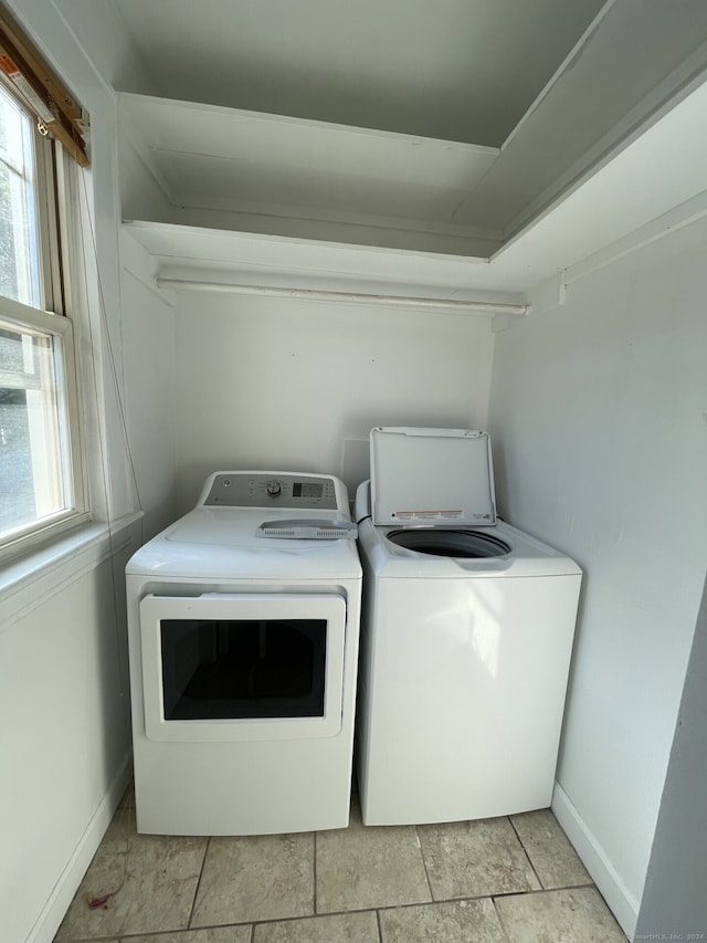 washroom with light tile patterned flooring, washing machine and dryer, and plenty of natural light