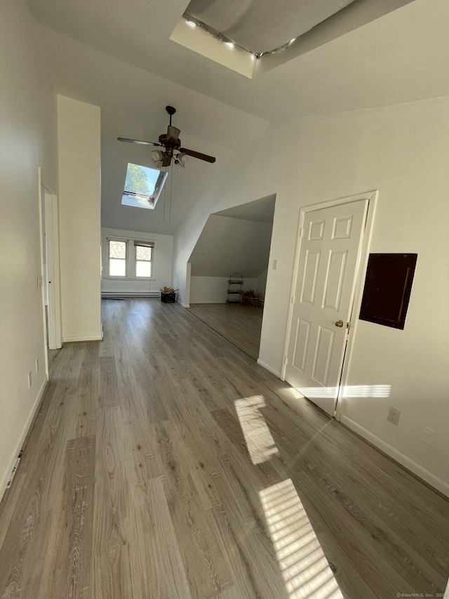 additional living space with ceiling fan, a skylight, and wood-type flooring