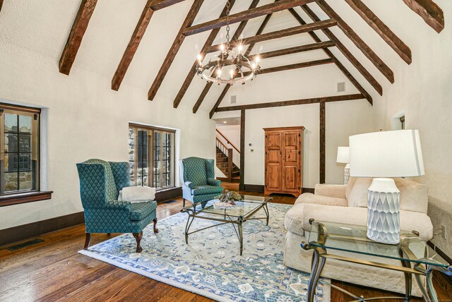 living room with wood-type flooring, a healthy amount of sunlight, high vaulted ceiling, an inviting chandelier, and beam ceiling