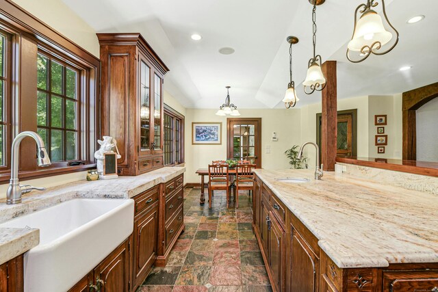 kitchen featuring sink, decorative light fixtures, light stone countertops, and dark tile patterned flooring