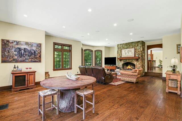 dining area with a stone fireplace and wood-type flooring