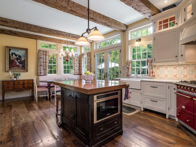 kitchen featuring hanging light fixtures, a kitchen island, white cabinets, and beam ceiling