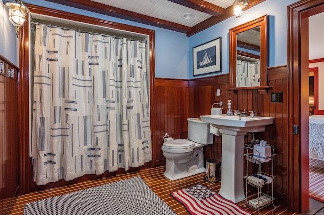 bathroom featuring beamed ceiling, wooden walls, toilet, and a shower with curtain