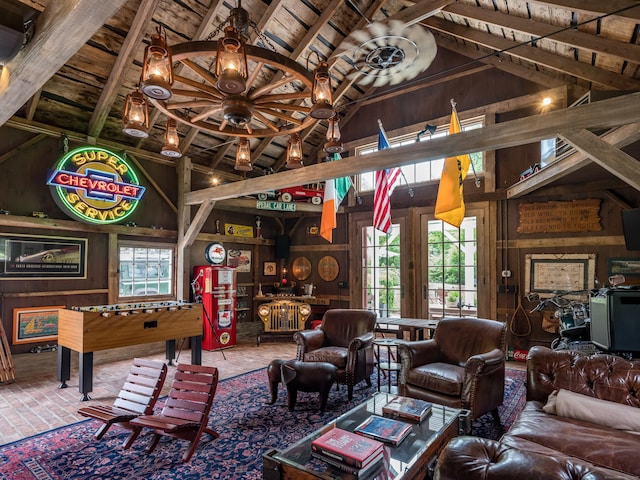 living room with beam ceiling, plenty of natural light, high vaulted ceiling, and wood walls