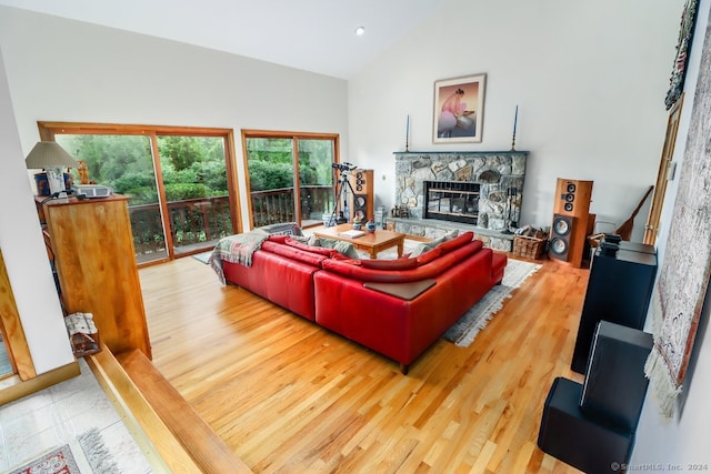 living room with wood-type flooring, vaulted ceiling, and a stone fireplace