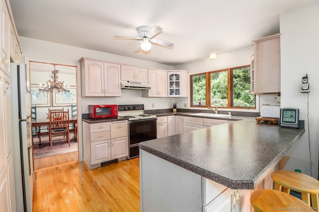 kitchen with kitchen peninsula, a kitchen bar, white appliances, ceiling fan with notable chandelier, and light hardwood / wood-style floors