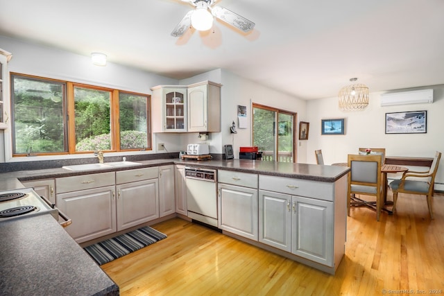 kitchen with white dishwasher, kitchen peninsula, sink, and a wealth of natural light