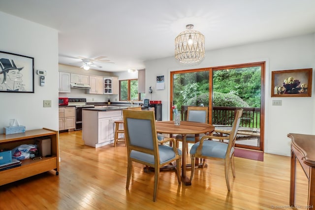 dining area with ceiling fan with notable chandelier and light hardwood / wood-style flooring