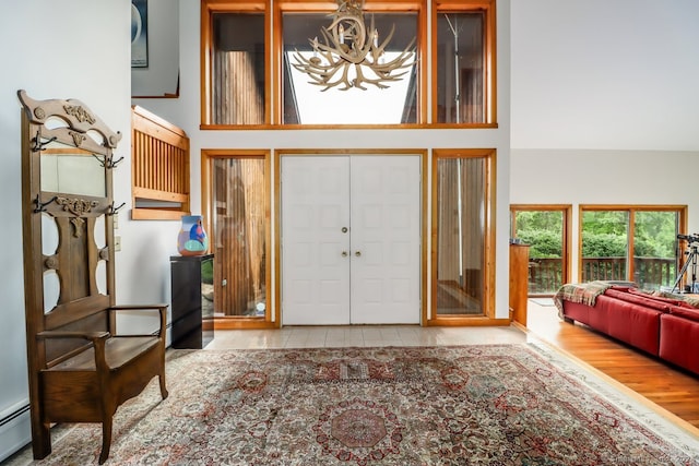 entrance foyer with a high ceiling, light hardwood / wood-style floors, and a baseboard radiator