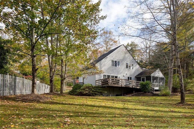 rear view of house with a deck, a sunroom, and a lawn