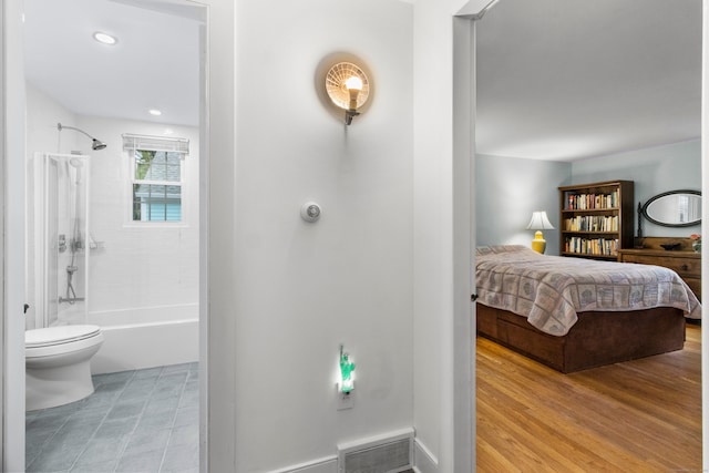 bedroom featuring connected bathroom and light hardwood / wood-style flooring