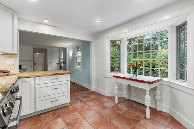 kitchen with butcher block counters, a healthy amount of sunlight, and tasteful backsplash