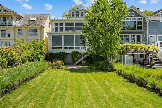 rear view of house with a sunroom and a yard