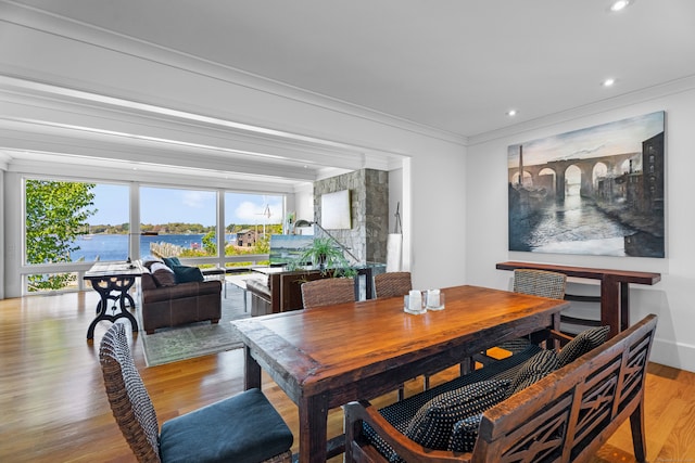 dining space with ornamental molding, light wood-type flooring, and a water view