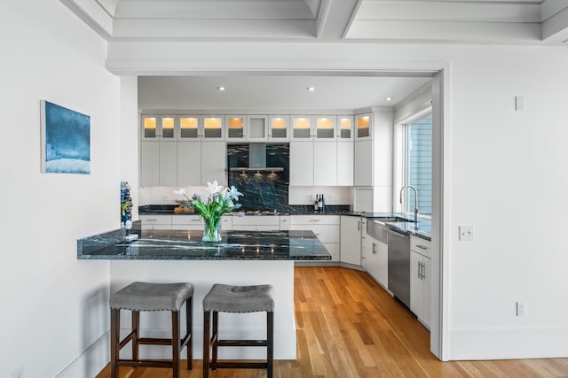 kitchen with dishwasher, kitchen peninsula, sink, white cabinetry, and light hardwood / wood-style flooring