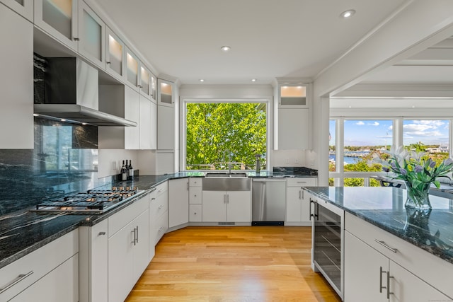 kitchen with white cabinets, stainless steel appliances, light hardwood / wood-style floors, and beverage cooler