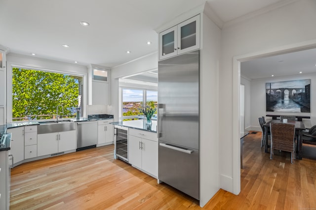 kitchen with white cabinets, light wood-type flooring, appliances with stainless steel finishes, and sink