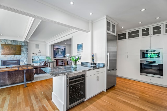 kitchen with stainless steel appliances, white cabinets, crown molding, light wood-type flooring, and wine cooler