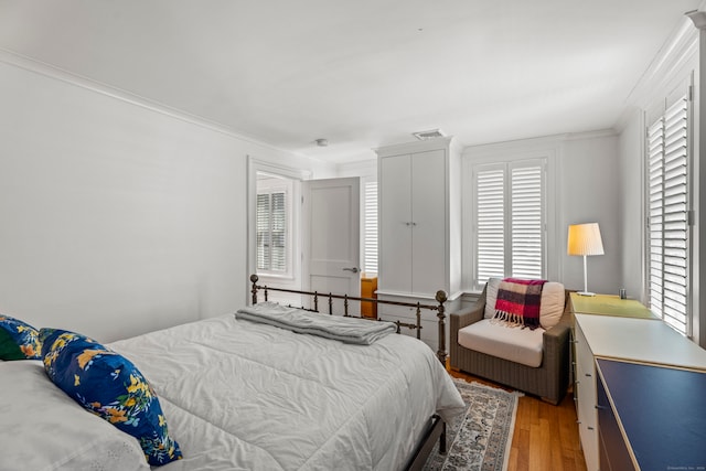 bedroom with wood-type flooring, multiple windows, and crown molding