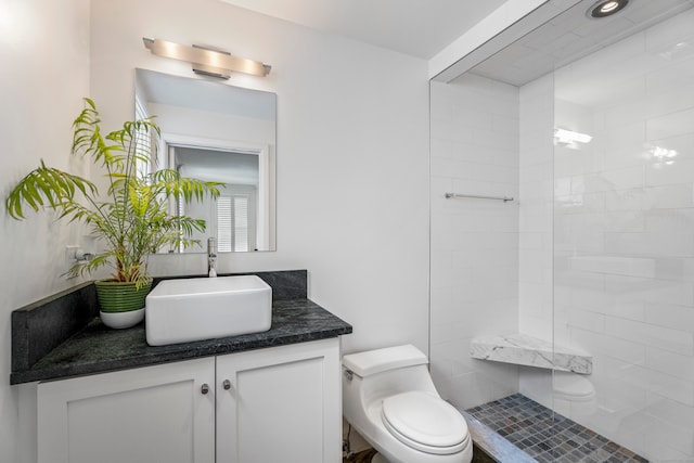 bathroom featuring toilet, vanity, and tiled shower