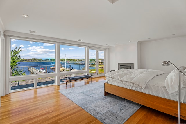 bedroom with a water view, wood-type flooring, and ornamental molding