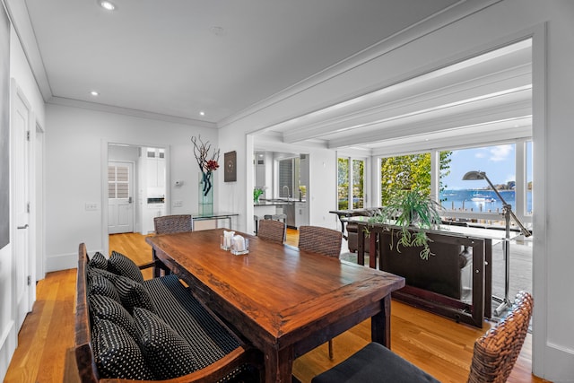 dining area featuring light hardwood / wood-style floors, a water view, and crown molding