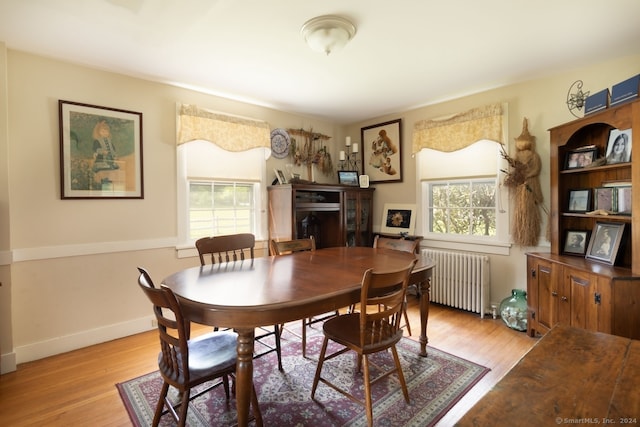 dining space with radiator heating unit and light wood-type flooring