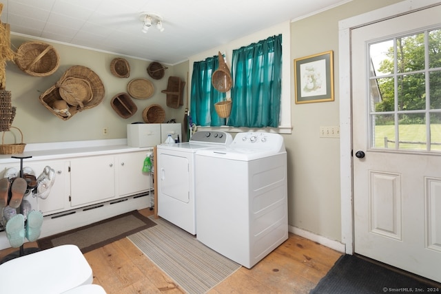 clothes washing area with independent washer and dryer, cabinets, and light hardwood / wood-style flooring