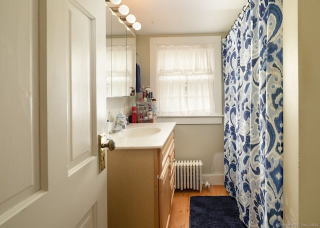 bathroom with large vanity, hardwood / wood-style floors, and radiator heating unit