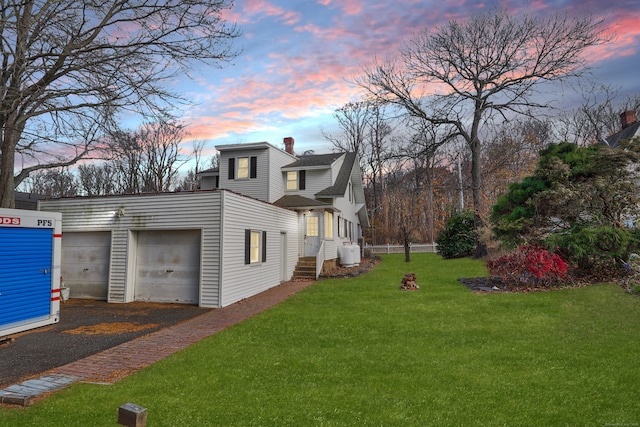 property exterior at dusk with a lawn and a garage