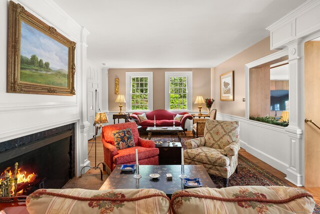 living room with a premium fireplace, dark hardwood / wood-style flooring, and decorative columns