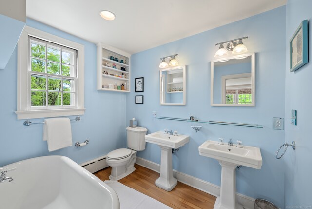 bathroom with a baseboard heating unit, a wealth of natural light, toilet, and hardwood / wood-style floors