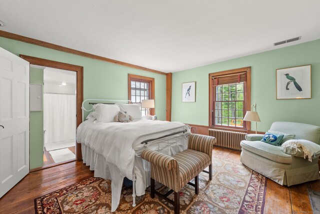 bedroom featuring crown molding, radiator heating unit, and wood-type flooring