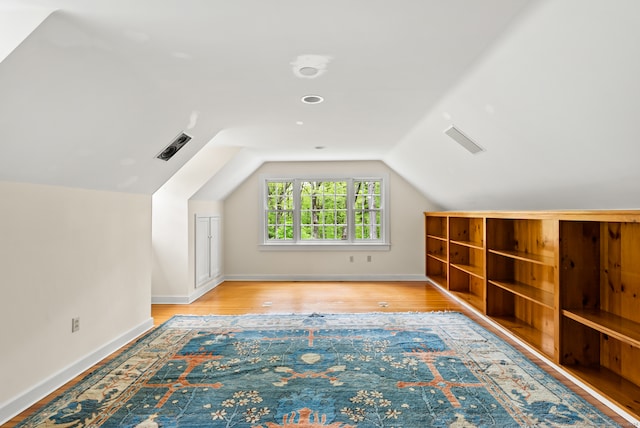 additional living space featuring vaulted ceiling and wood-type flooring