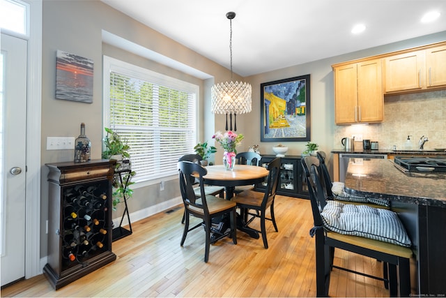 dining space featuring light hardwood / wood-style floors, sink, and a notable chandelier