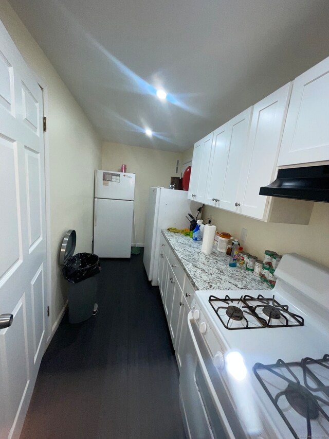 kitchen featuring white cabinetry, light stone countertops, custom range hood, white appliances, and dark hardwood / wood-style floors