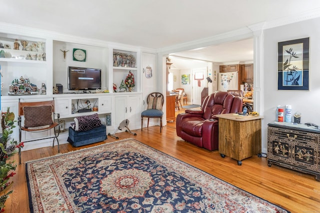 living room with wood-type flooring, ornamental molding, and built in shelves