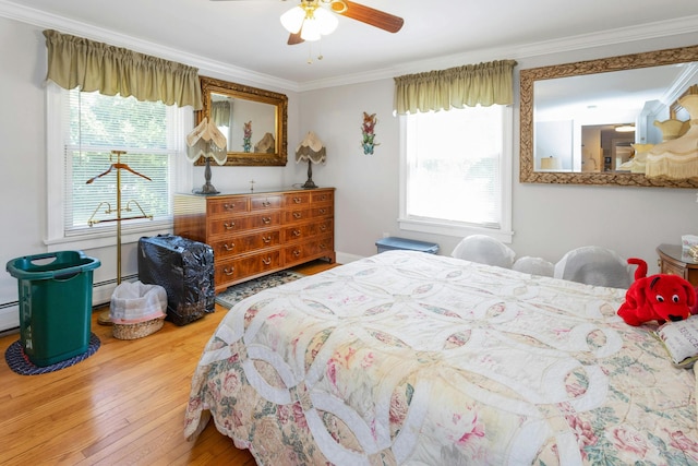 bedroom with a baseboard radiator, multiple windows, hardwood / wood-style flooring, and ornamental molding