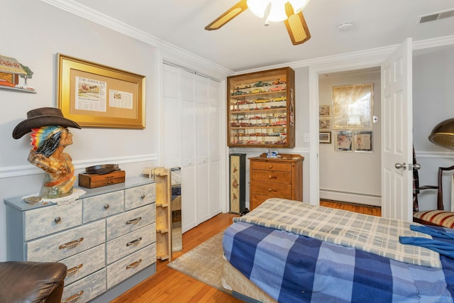 bedroom with a closet, hardwood / wood-style flooring, a baseboard radiator, ornamental molding, and ceiling fan